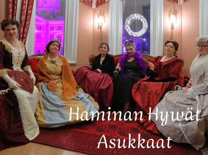 Yhdistyksen jäseniä krinoliinipuvuissa salongissa